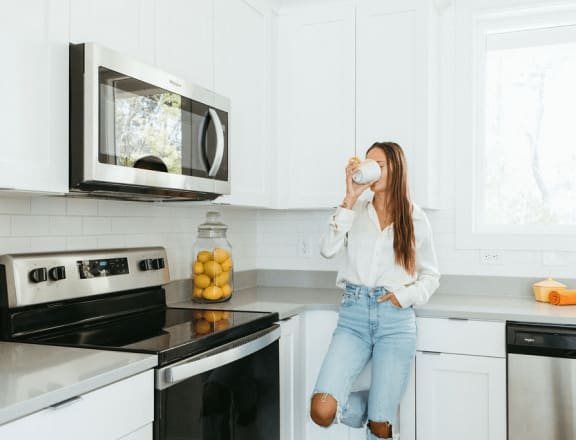 person sitting on a kitchen counter drinking a cup of coffee