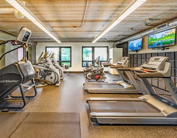 a gym with treadmills and other exercise equipment on the floor