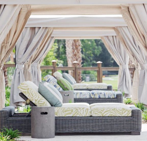 a gazebo with couches and pillows on a patio