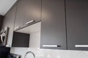 A modern kitchen with dark grey cabinets and a black countertop.