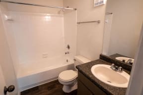 Northlake Apartments Jacksonville, Florida bathroom with tub, dark cabinets and counter, and wood-inspired flooring