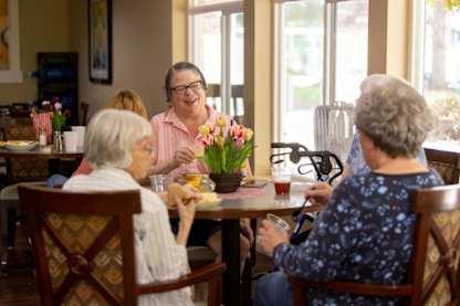 A group of elderly people are sitting around a table eating and drinking.