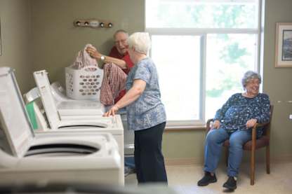 A woman is folding laundry in a room with a washing machine.