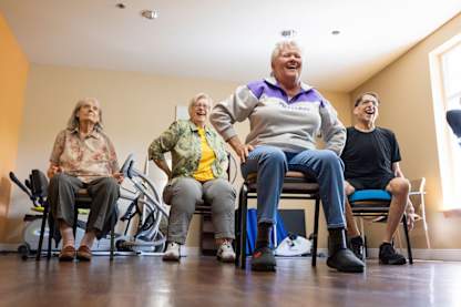 Four elderly people are exercising on stationary bikes in a room.