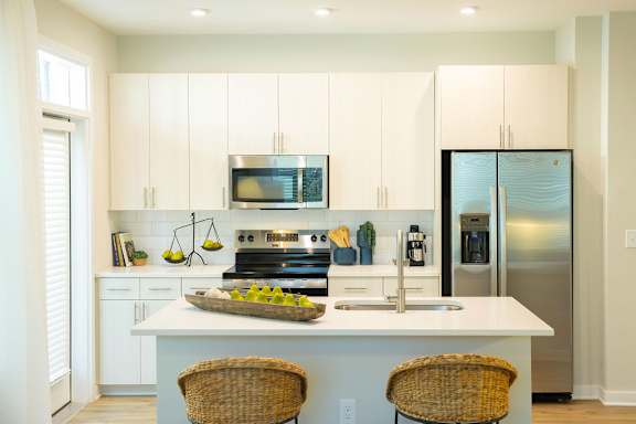 A kitchen with white cabinets and a stainless steel refrigerator.