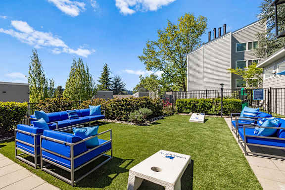a patio with blue lounge chairs and a table on the grass