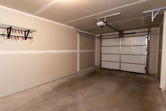 A garage with a white door and a concrete floor.