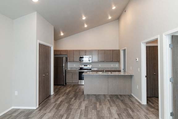 A kitchen with a refrigerator, microwave, oven, and sink.