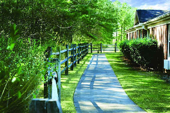 a sidewalk in front of a house with a wooden fence