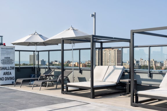 a roof top deck with lounge chairs and umbrellas