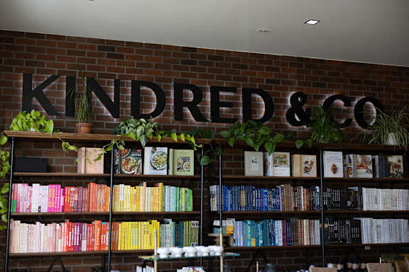 A bookshelf filled with books under a sign that says "KINDRED & CO".
