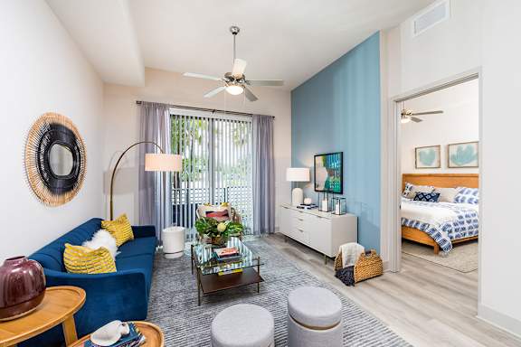 A living room with a blue couch and a ceiling fan. at Morea Apartments, Pompano Beach, Florida
