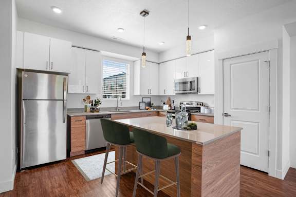 A modern kitchen with a wooden island and green barstools.