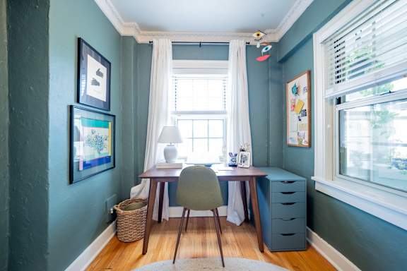 A room with a desk and chair in front of a window.