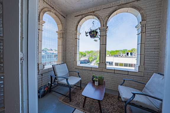 A balcony with two chairs and a table with a potted plant on it.