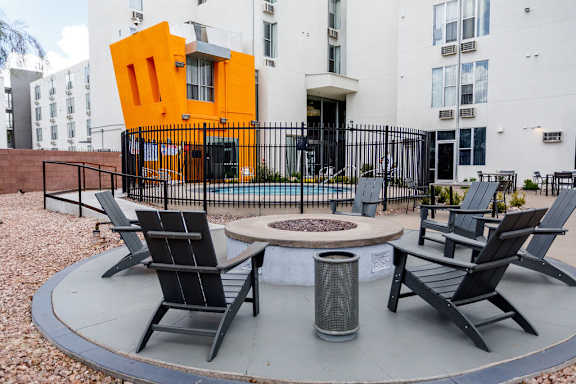 A modern outdoor seating area with black chairs and a fire pit.