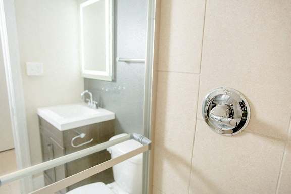 A bathroom with a toilet, sink, and mirror.