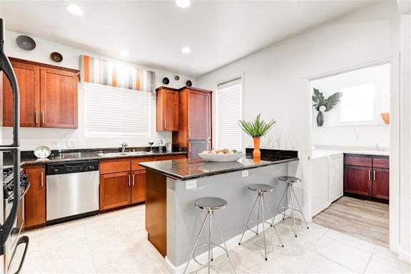 a kitchen with an island and wooden cabinets at Croix Townhomes, Henderson, NV