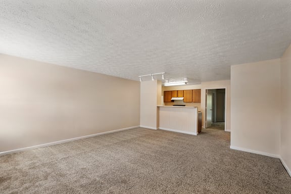 A room with a carpeted floor and a small desk with a chair.