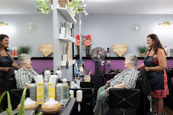 A woman is standing in front of a purple wall in a salon.