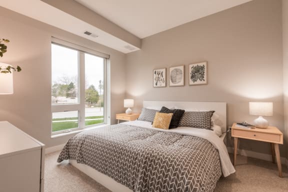 Bedroom with large window, bed, and nightstands with lamps