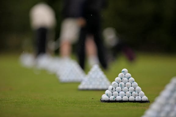 a row of golf balls on the green with players in the background