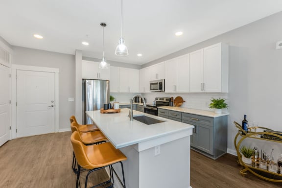 a kitchen with white cabinets and a large white island with two yellow chairs in front of it