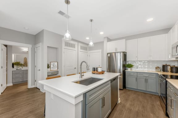 a kitchen with white cabinets and a large white island with a stainless steel sink