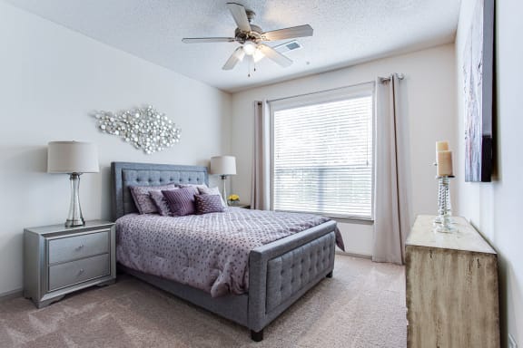 a bedroom with a large window and a ceiling fan