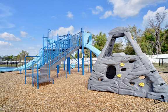 A playground with a blue slide and a grey rock climber.