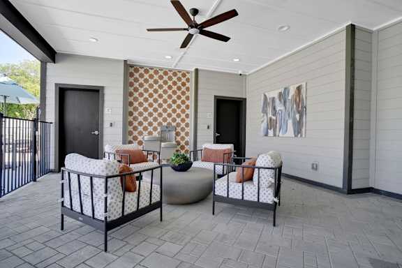 A patio with a black metal fence and a ceiling fan.