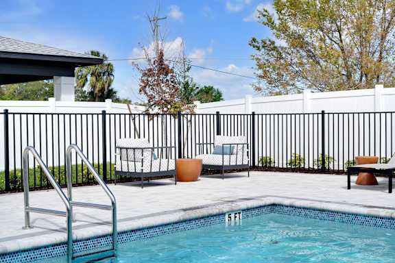 A pool with a ladder and chairs around it.