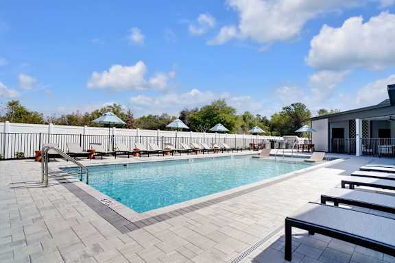 A large outdoor swimming pool with sun loungers and umbrellas.