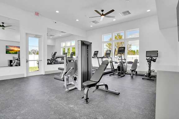 A gym with a variety of equipment including a squat rack, bench press, and a rowing machine.