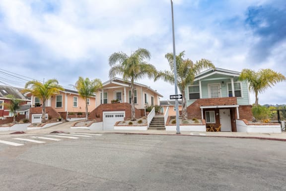 a row of houses with palm trees on the side of a street