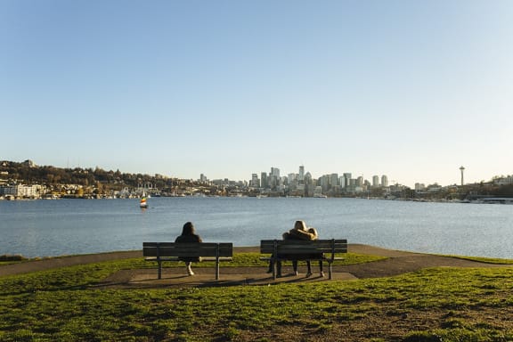 two people sitting on park benches near a body of water at The Hayes on Stone Way, Seattle, WA, 98103