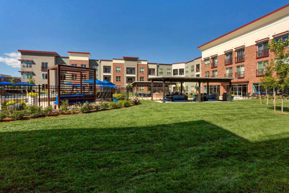 Westlake Greens Courtyard with grass, fenced in pool, pergola, and apartments behind