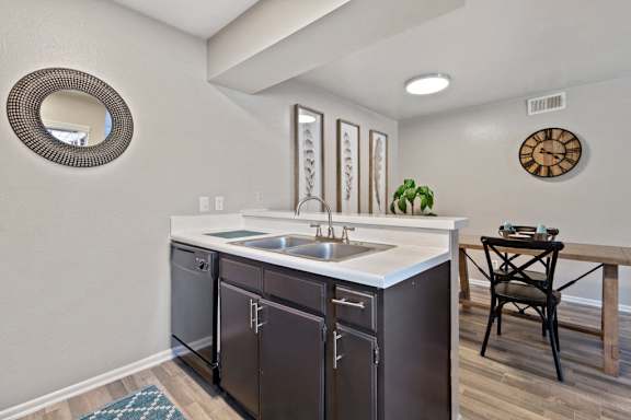 Kitchen sink with dark wood cabinets and dining area at The Colony Apartments, Universal City