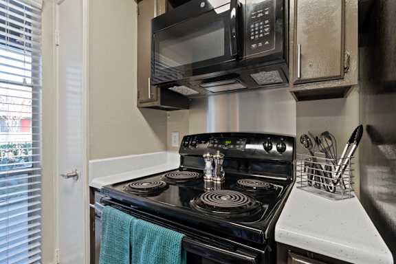 Electric stove with coil burners and overhead microwave at The Colony Apartments, Texas