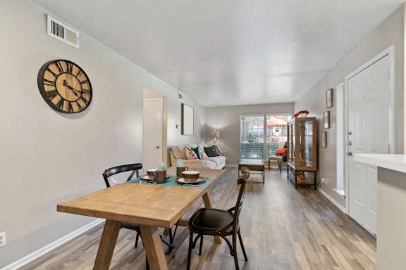 Open concept living and dining area with wood style flooring at The Colony Apartments, Texas, 78148