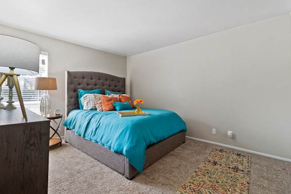 Bedroom with tufted headboard and colorful accent rug at The Colony Apartments, Universal City