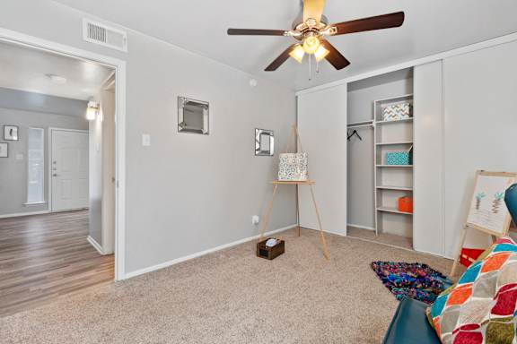 Bedroom with ceiling fan and open closet shelving at The Colony Apartments, Texas
