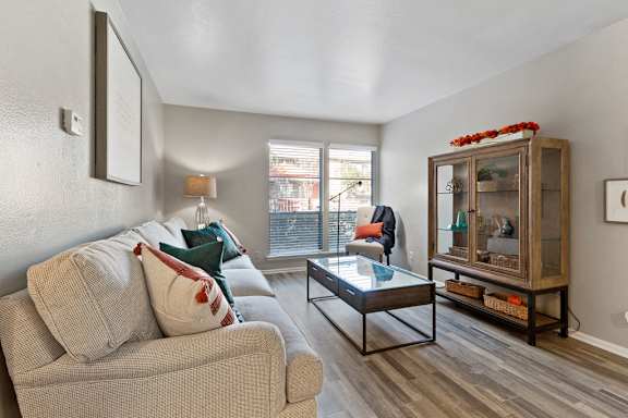 Living room with modern furnishings and glass display cabinet at The Colony Apartments, Texas, 78148