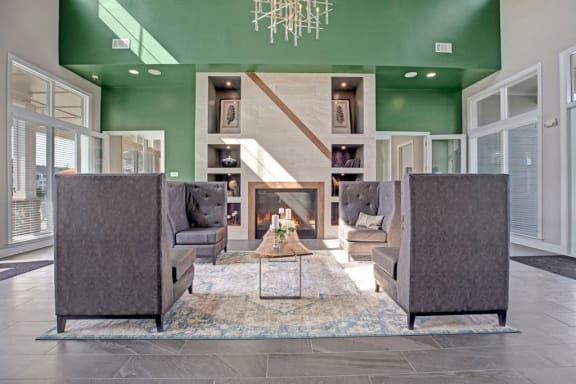 Lobby area that has couch like chairs, table in the center, fire place, dark concrete like floors, and big windows at Ascent at Mallard Creek Apartments in Charlotte, NC