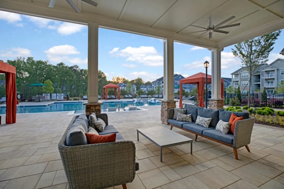 Pool view at Ascent at Mallard Creek Apartment Homes. Couches, table, cabanas, big pool, outside fans, and tile concrete flooring. At Ascent at Mallard CreekCharlotte, 28262