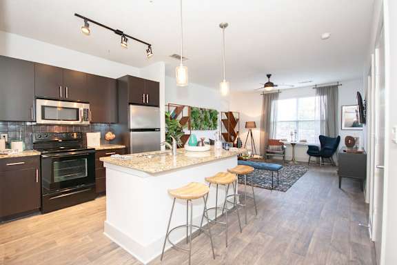 a kitchen and living room with an island and stools at Glenwood Park Lofts, Atlanta, GA, 30316