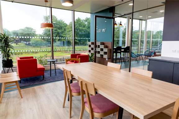 a large wooden table with chairs in front of a glass wall