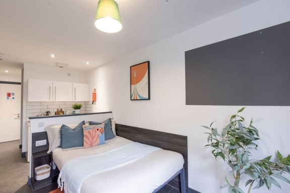 a bedroom with a bed and a kitchen in the background