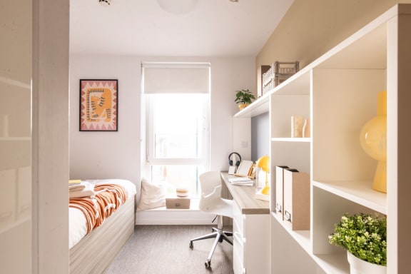 a small bedroom with a desk and a window