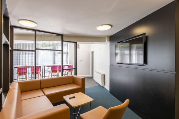 a room with a sofa and two chairs in front of a tv